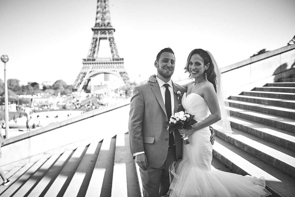 Photo noir et blanc d'un couple de mariés posés sur les escaliers du Trocadéro face à la Tour Eiffel