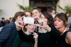 Groupe d'invités prenant un selfie joyeux avec un smartphone pendant une réception de mariage