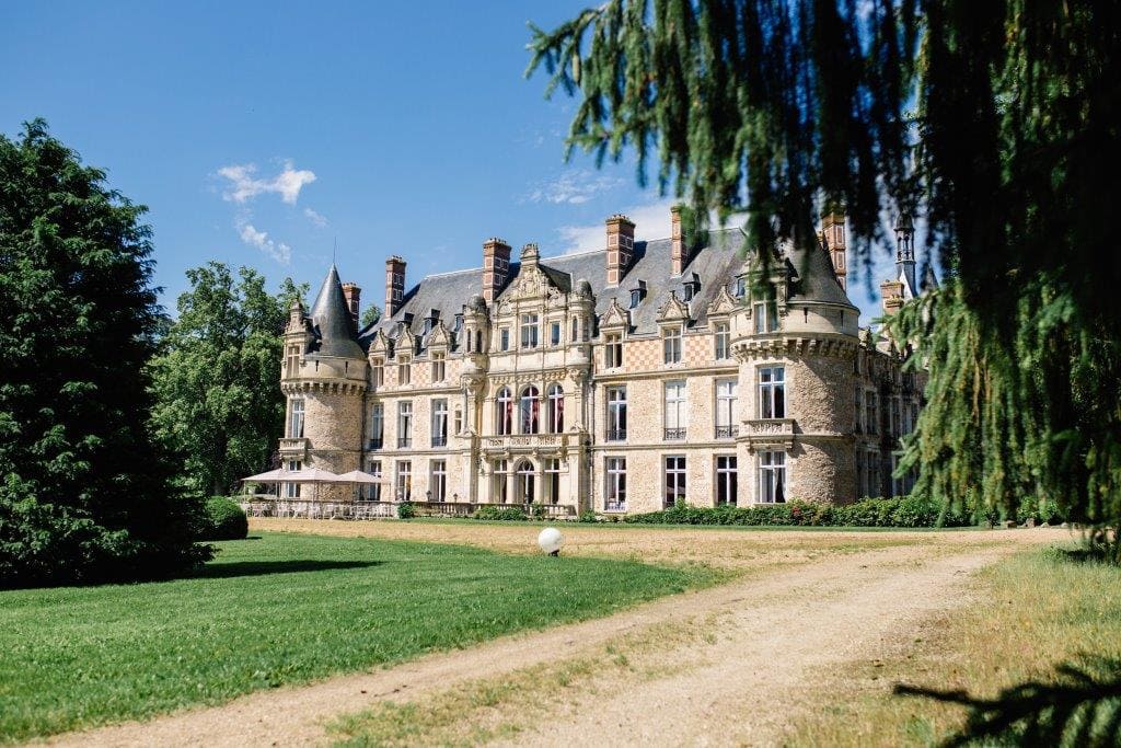 Elegant French wedding château surrounded by lush gardens and abundant greenery.